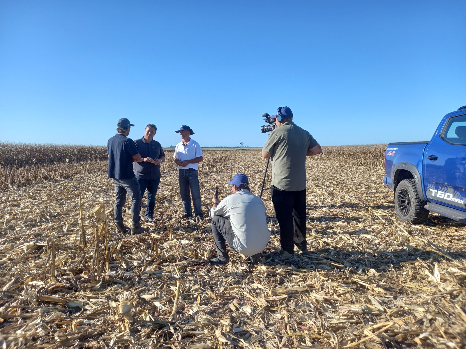 Entrevista vinculada a NK en un campo después de la cosecha, con un equipo de cámaras.