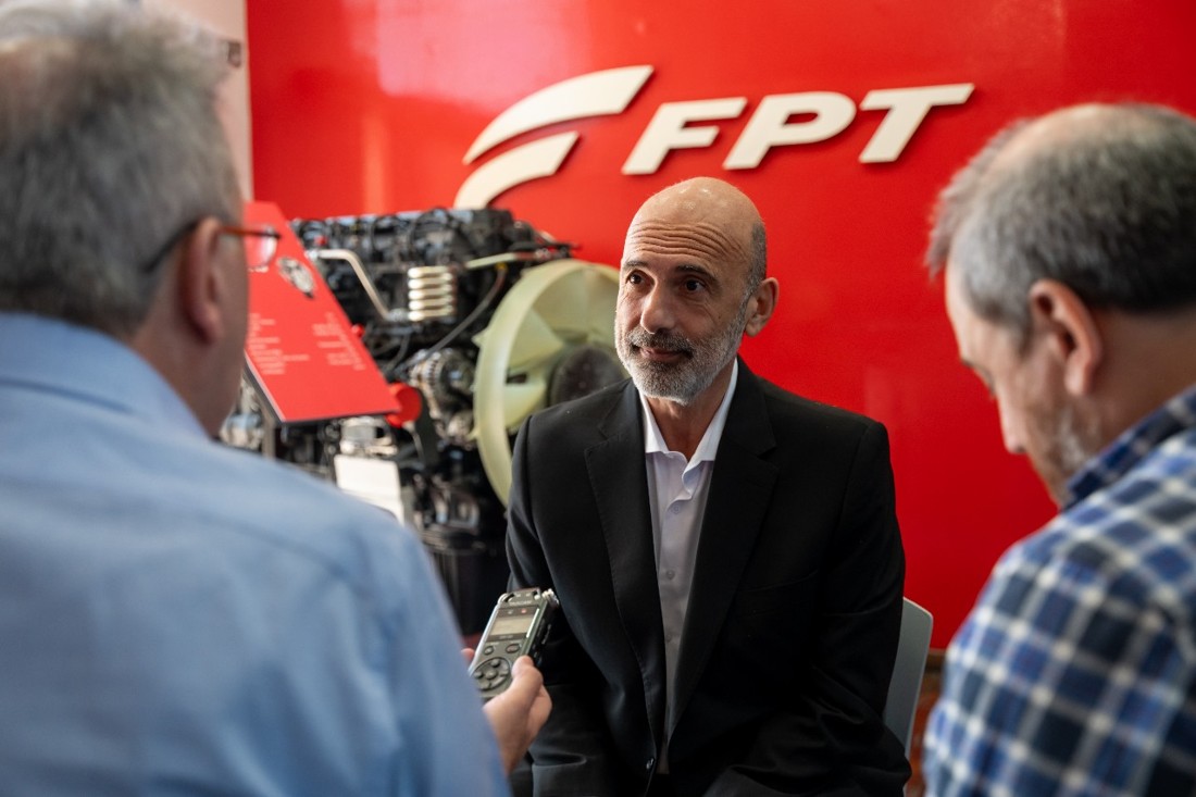 Conversación con periodistas frente al logo de FPT.
