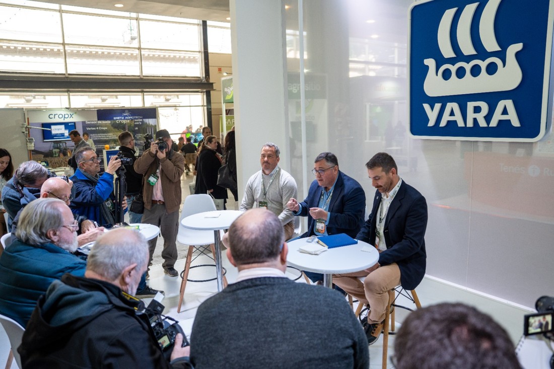 Voceros de Yara dialogan con periodistas frente al logo de la compañía en el Congreso de AAPRESID.